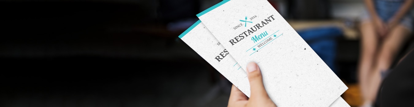 Person holding tri-fold disposable restaurant menus