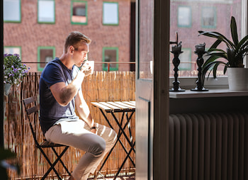 man drinking coffee on a balcony