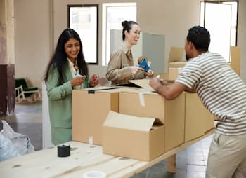 women at counter helping man box packages