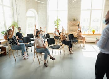 class with adults raising hands