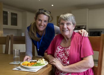 woman small business owner delivers meal to senior citizen