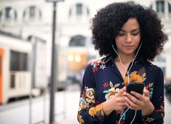woman listens to podcast on earbuds