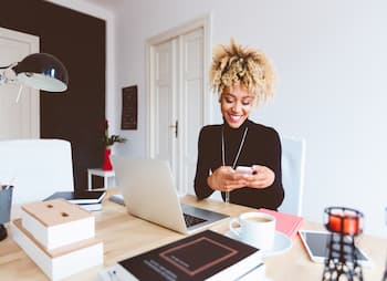 Woman texting on her phone at a desk 