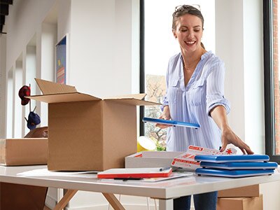 Moving boxes and supplies Young woman packing household items in boxes