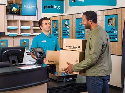 Empleado sostiene la puerta para un cliente que lleva cajas