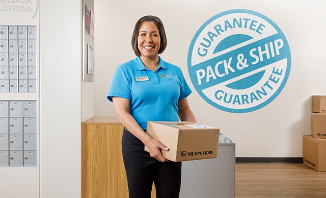 The UPS Store assocuate holding a box.