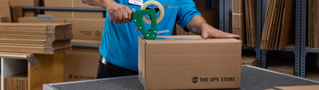 The UPS Store associate taping a shipping box