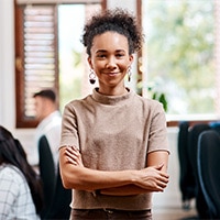 Young woman standing in an office with her arms folded. 