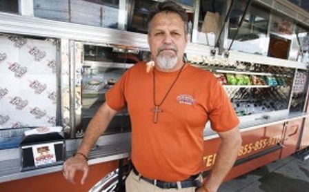 Smiling man standing in front of a food truck