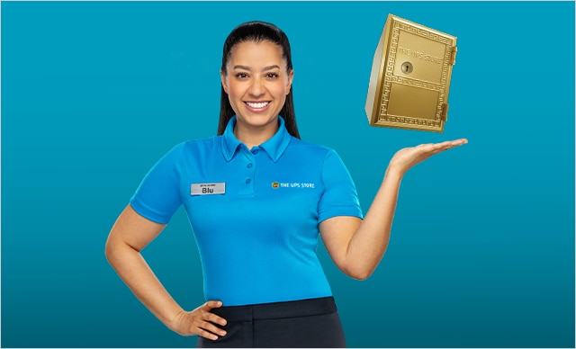 BLU WITH ONE HAND ON HER HIP AND THE OTHER OUT TO THE SIDE WITH GOLD THE UPS STORE MAILBOX HOVERING OVER THE TOP.