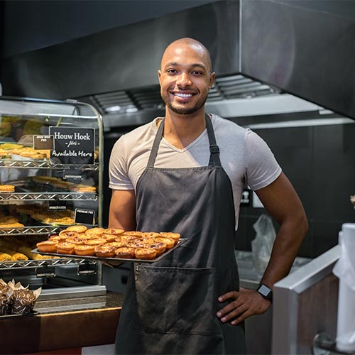 Baker holding baked goods in a bakery