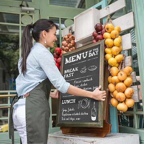 Woman hanging a menu outside her store