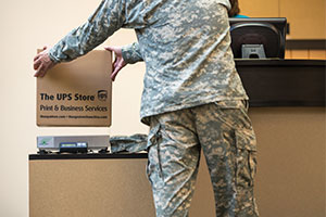 Hombre con uniforme militar colocando un paquete sobre una báscula en una tienda