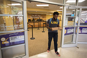 Estudiante sosteniendo un paquete mientras sale de la tienda en LSU