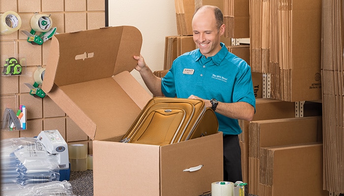  The UPS Store associate packing luggage to ship.